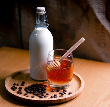Elegant setup featuring a milk bottle and honey glass on a wooden tray with coffee beans.